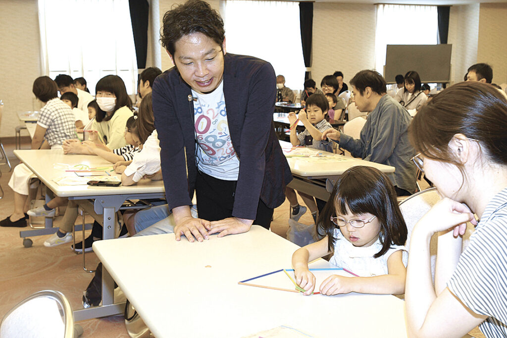 横山さん(左)の教えを受けながら図形づくりに挑戦する親子