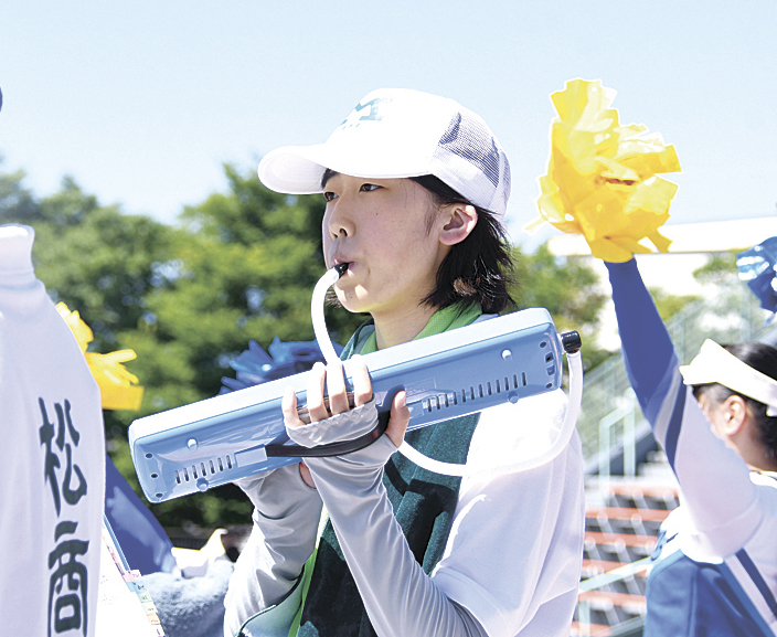 真剣な面持ちでグラウンドを見つめながら演奏する金原さん
