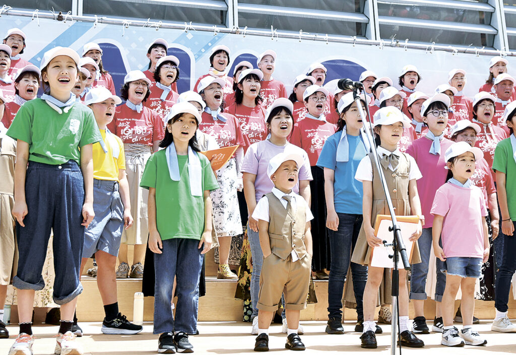 真夏の太陽の下、元気に歌う出演者たち