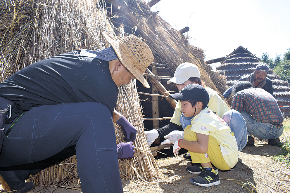 かやぶきを体験し、縄文時代の生活を学ぶ参加者
