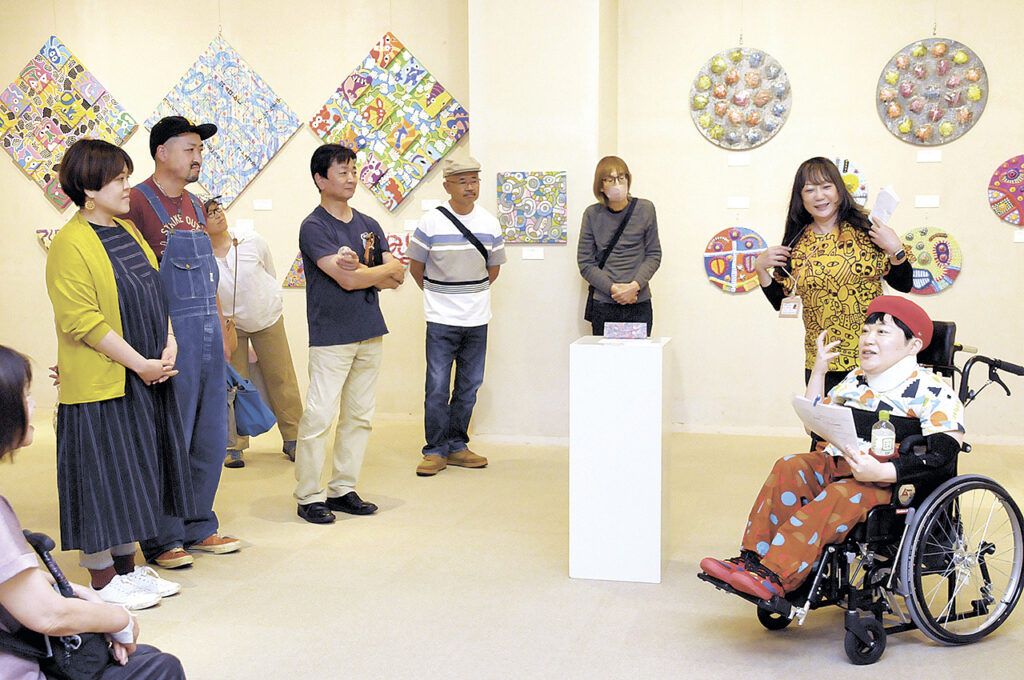 作品の展示会場で制作秘話を語るカミジョウさん（右）