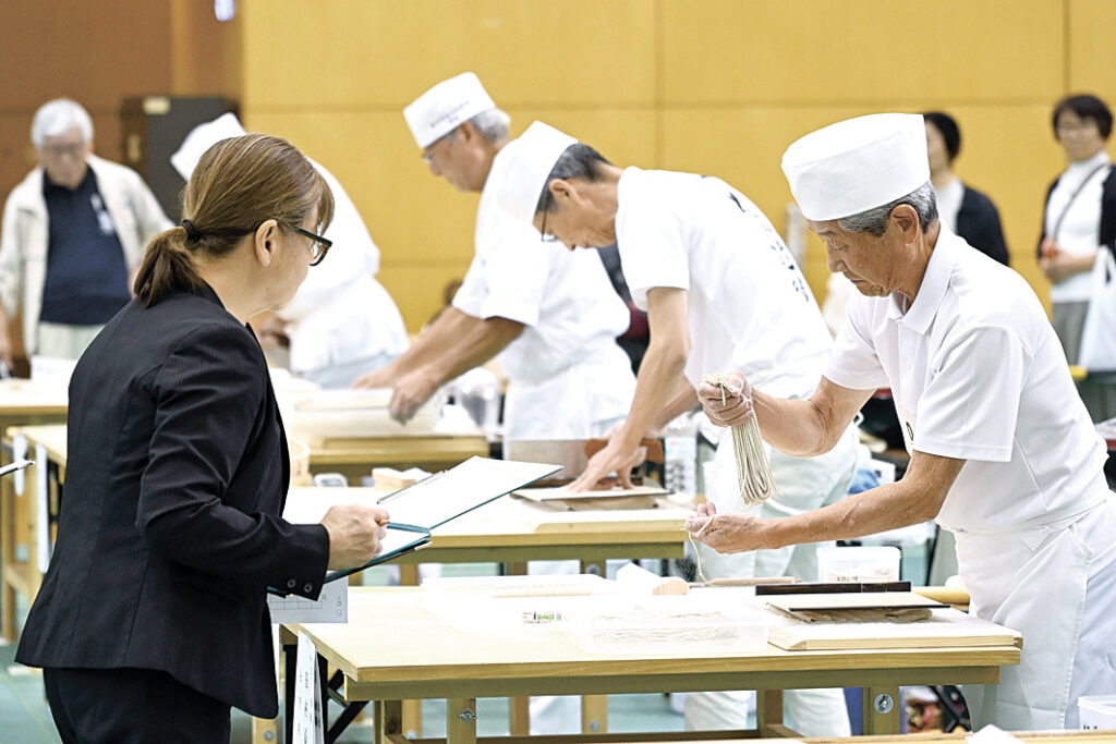 真剣な表情でそばを打つ受験者たち