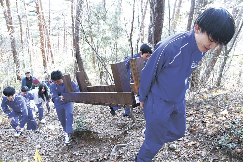 力を合わせてベンチを運ぶ生徒たち