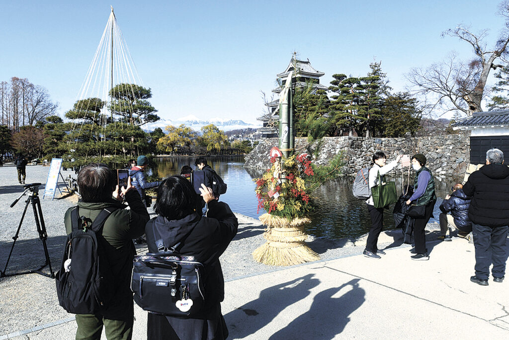 設置されたばかりの門松を撮影する観光客
