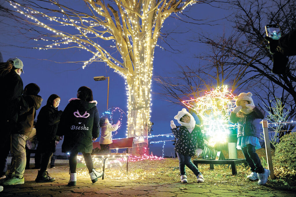 イルミネーションの前で記念撮影する家族連れ