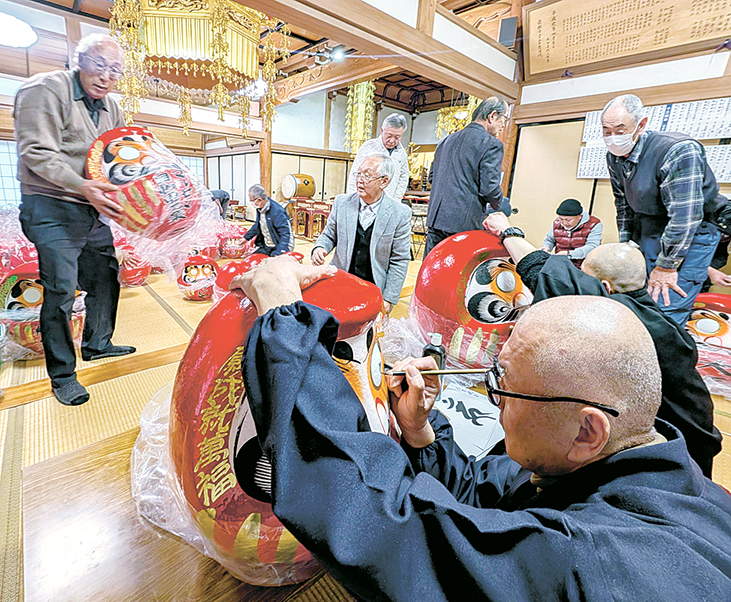 だるまに目入れ作業を行う関係者たち