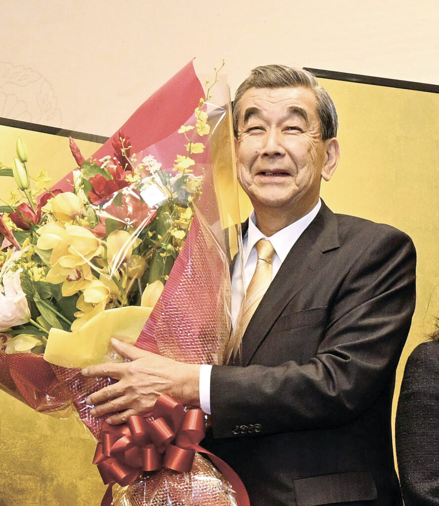 家族からの花束を手に笑顔を見せる中山氏