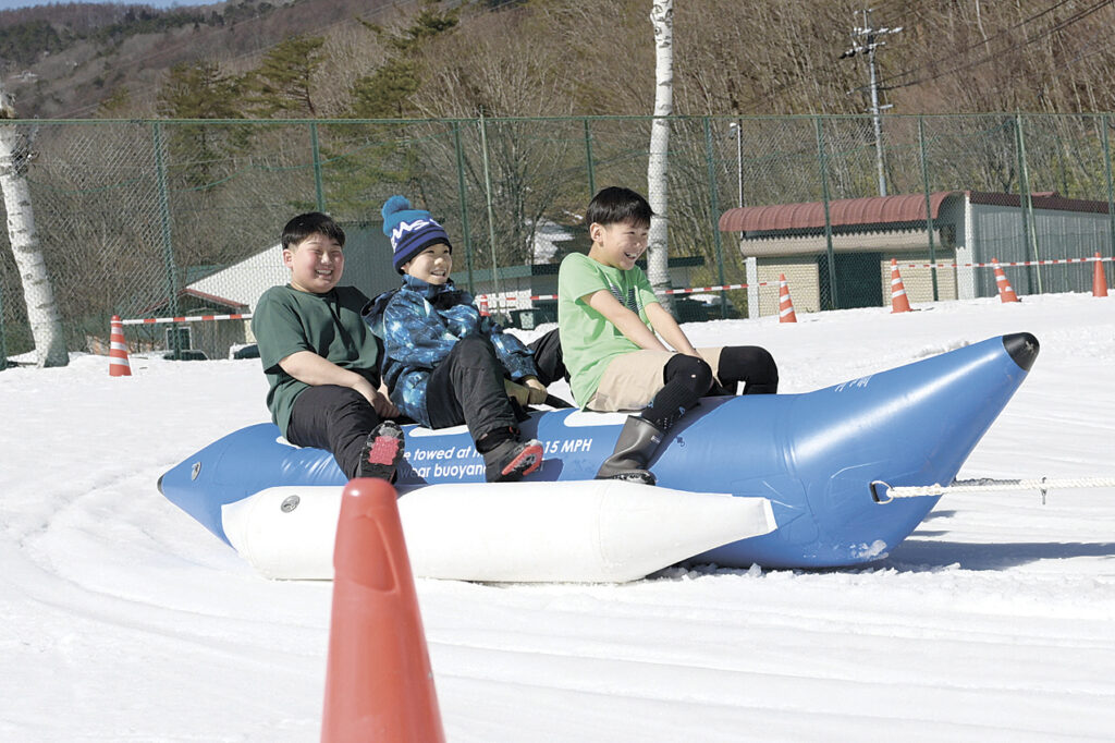 雪上を走るバナナボートを薄着で満喫する子供たち